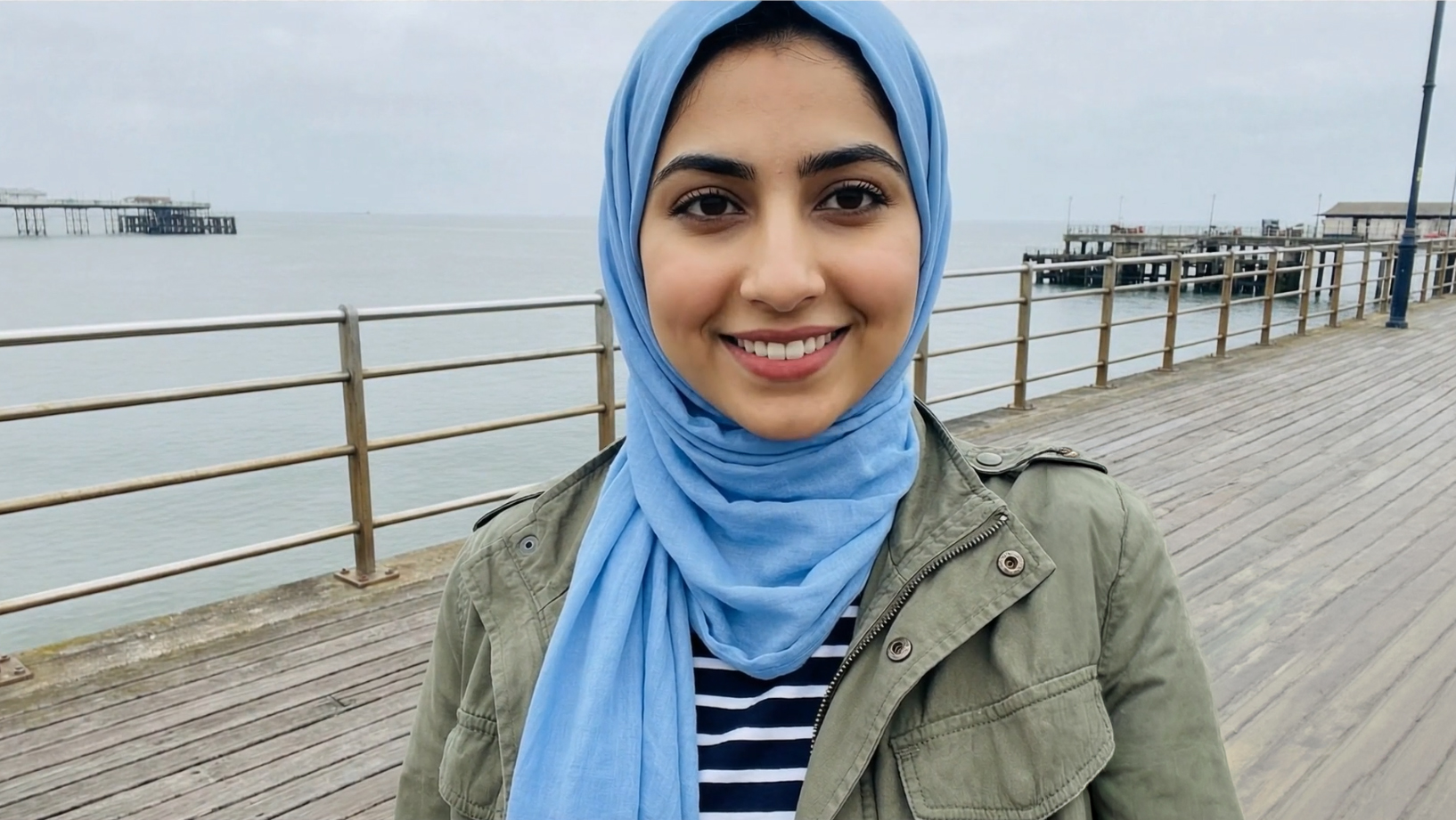 Clara Sediqa, eighteen, smiling on a pier by the sea